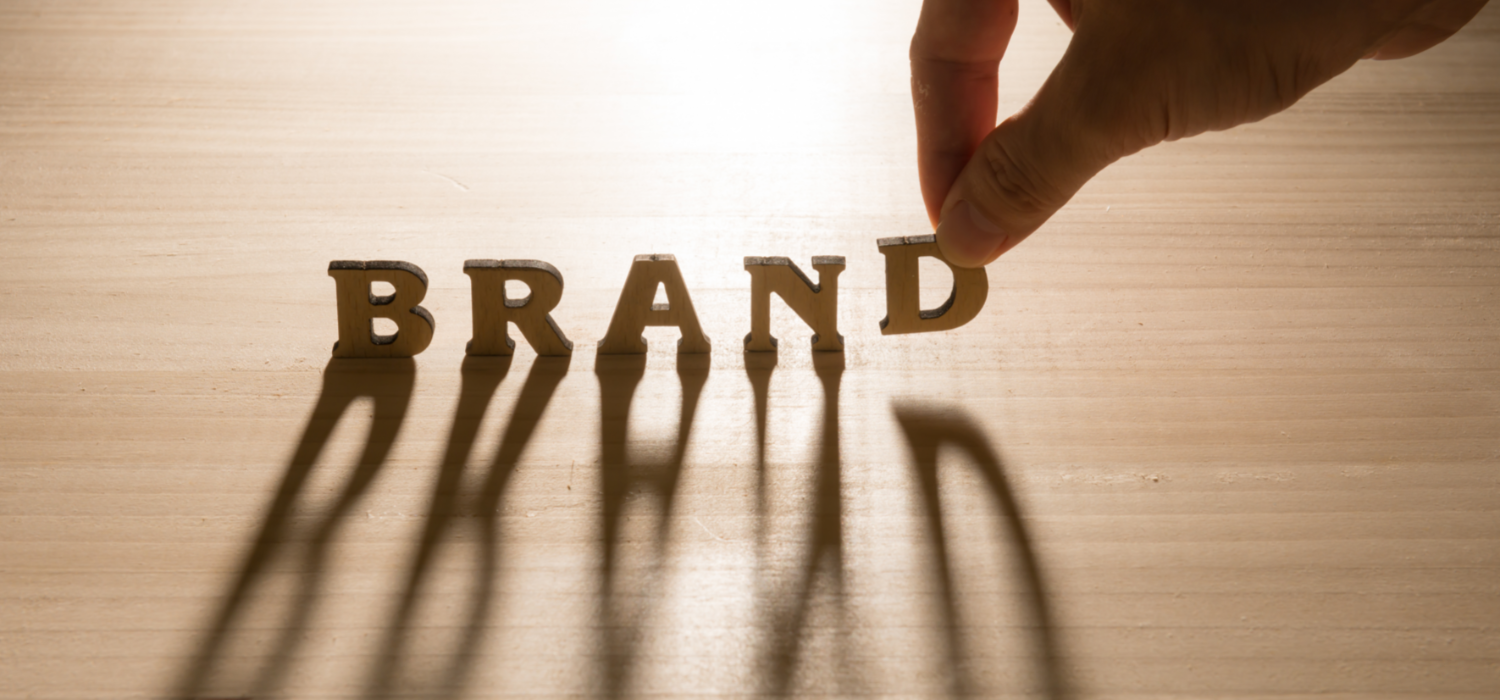 一隻手正把木製字母放上桌面,拼出「BRAND」字樣