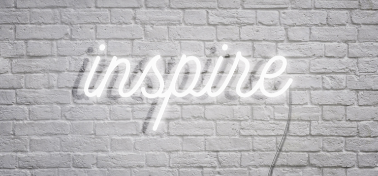 白色磚牆上亮著白色霓虹燈字「inspire」